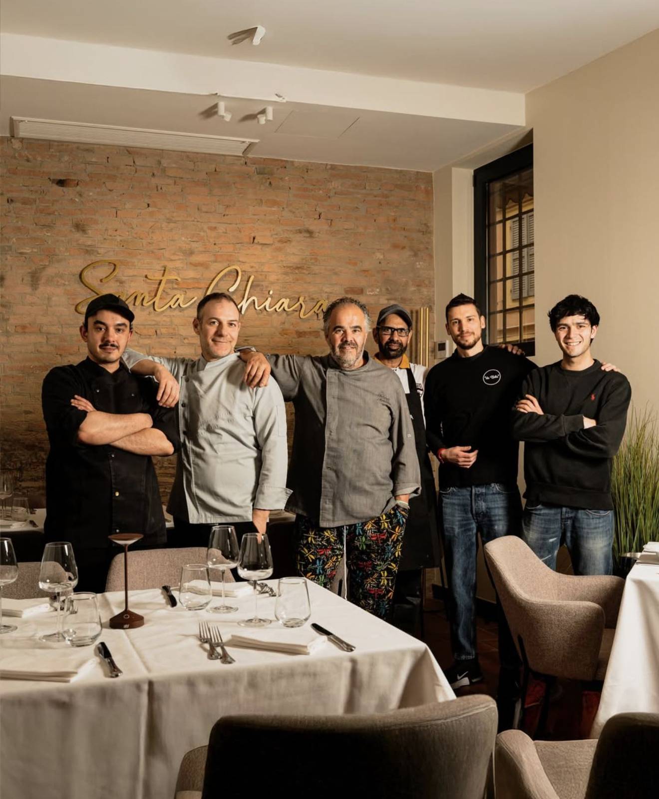 La sala rinnovata dell'Osteria Santa Chiara con l'insegna in ottone sul mattone a vista