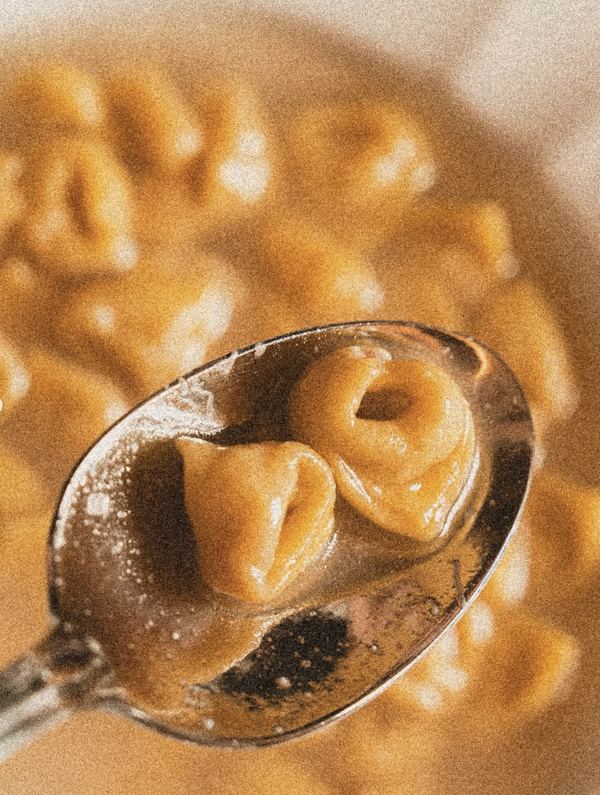 Tortellino in brodo di cappone sul cucchiaio